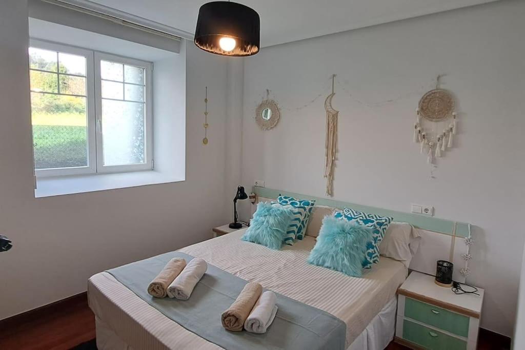 una camera da letto con un letto con cuscini blu e una finestra di Apartamento en Mioño a Castro-Urdiales