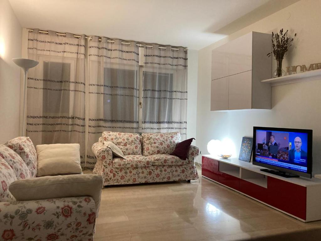 ein Wohnzimmer mit einem Sofa und einem TV in der Unterkunft Giovigemini Apartment in Treviso