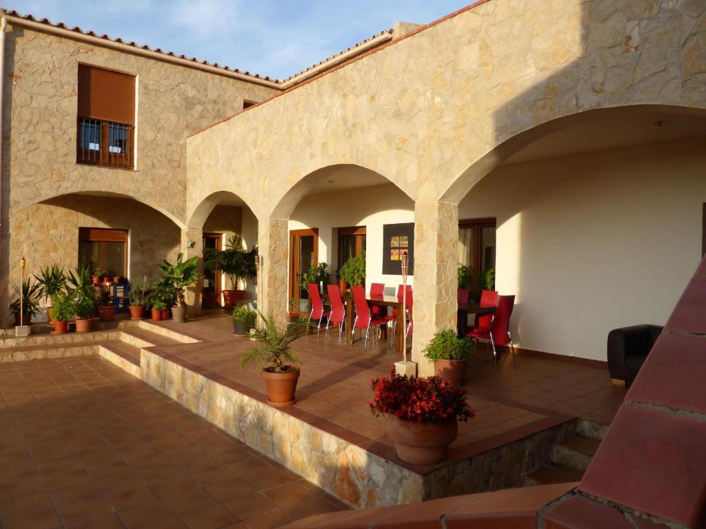 an outdoor patio with red chairs and potted plants at B&B Casa Rural Mas del Rey in Cálig