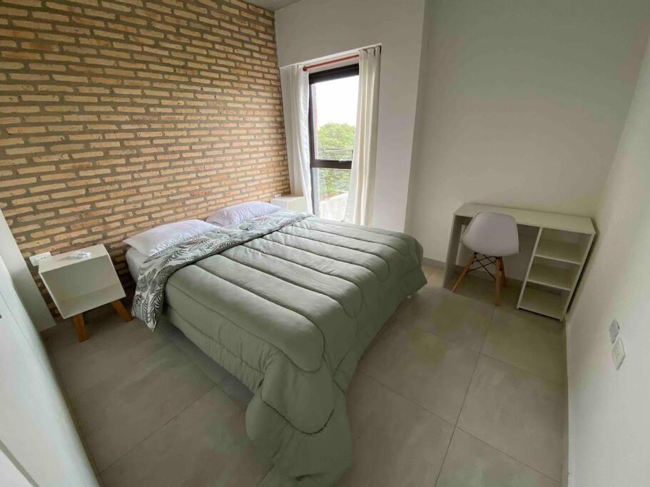 a bedroom with a bed and a brick wall at Apartamento 2 habitaciones en Asunción. in Asunción