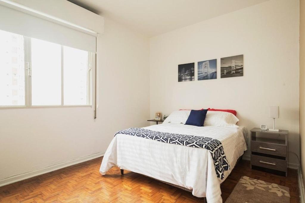 Habitación blanca con cama y ventana en Dona Acibe Apartments by BnbHost, en São Paulo