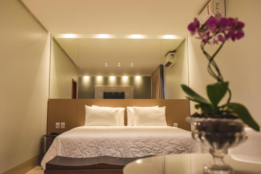 Hotel D'Leon في جوروبي: غرفة نوم بسرير و مزهرية عليها ورد