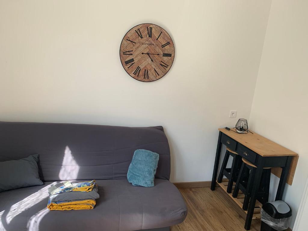 a living room with a couch and a clock on the wall at Studio en plein cœur d’aubusson in Aubusson