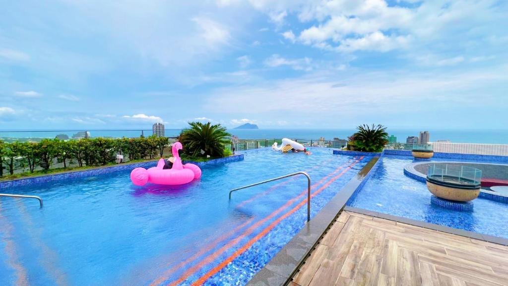 a large swimming pool with a pink inflatable raft at 光嶼海溫泉海景無邊際泳池豪華套房 in Hsin-hsing