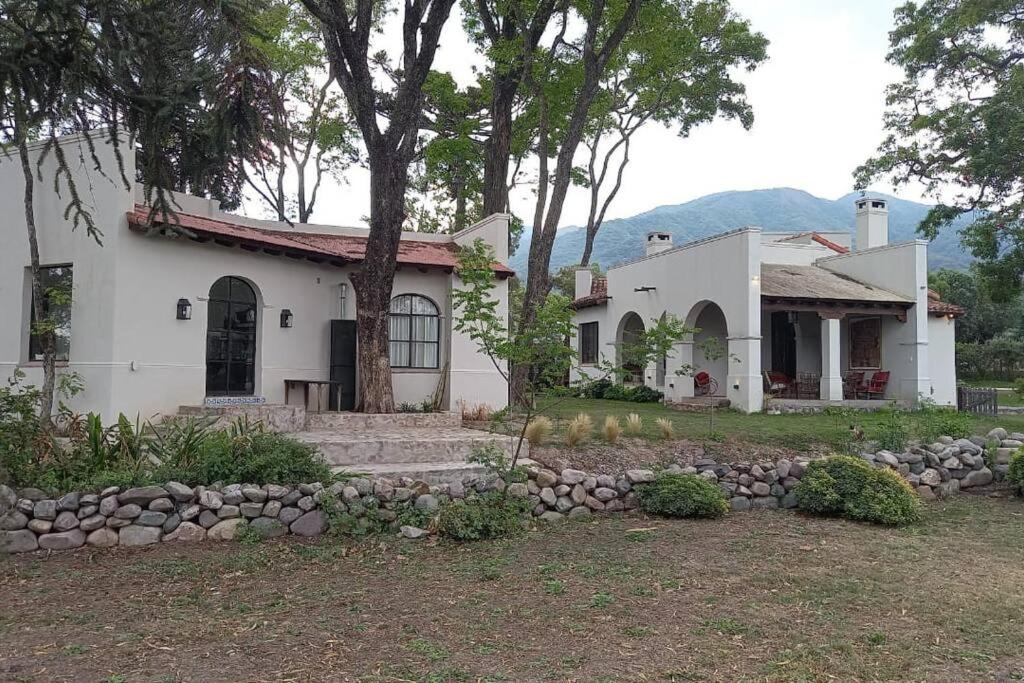 Una casa blanca con un árbol delante. en La Justina - Casa de Campo en San Lorenzo en San Lorenzo