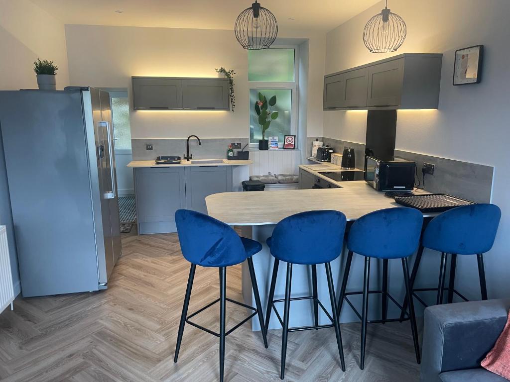 a kitchen with a table and four blue bar stools at Springlea in Oban