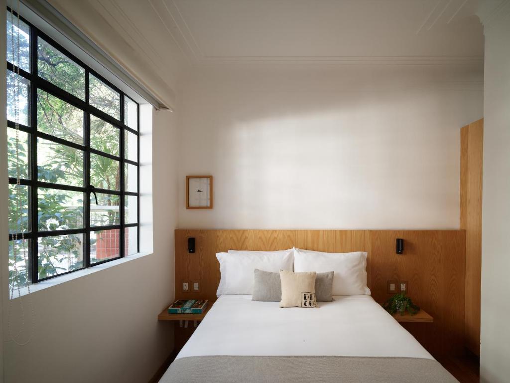 a bedroom with a white bed and a window at Casa Decu in Mexico City