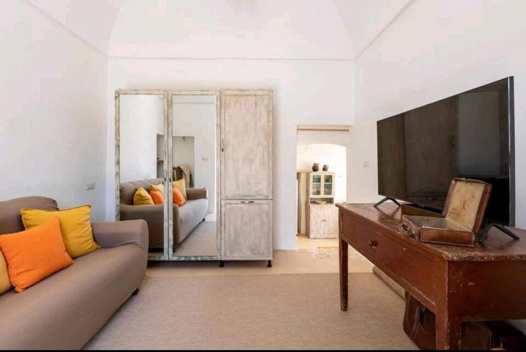 un salon avec un canapé et une télévision à écran plat dans l'établissement Trullo Zurlo, à Ostuni