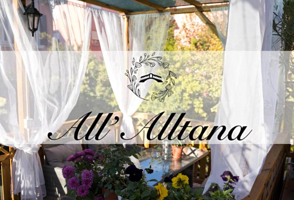 マルゲーラにあるAll’Altana b&b apartmentの白いカーテンと花のテーブル付きの窓