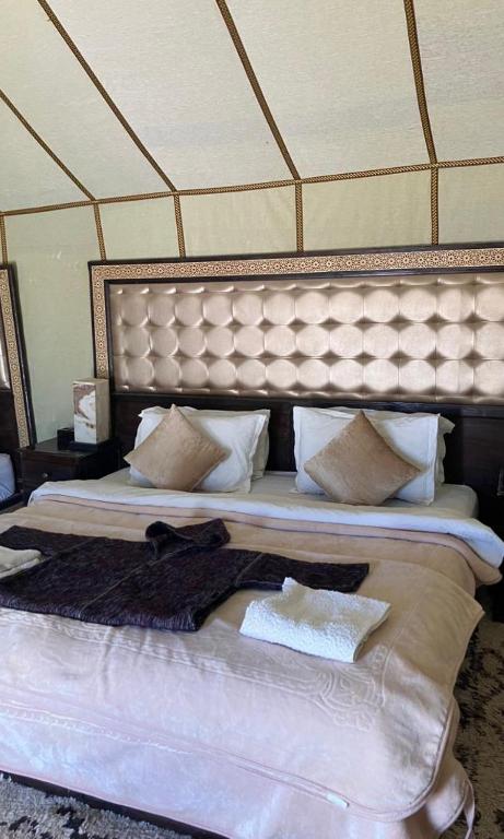 a large bed with a large headboard in a room at Luxury Sahara Camp in Merzouga