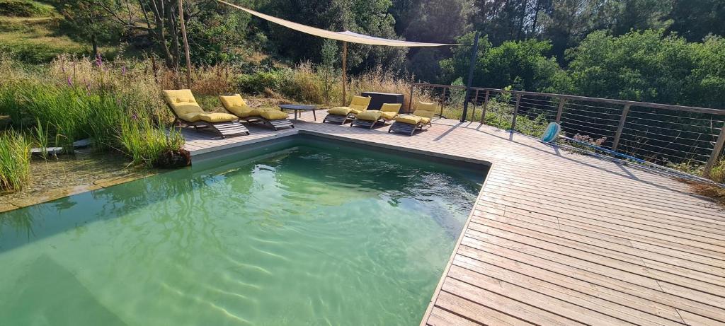a swimming pool with chairs and a wooden deck at Gîte du Puy in Saint-Fortunat-sur-Eyrieux