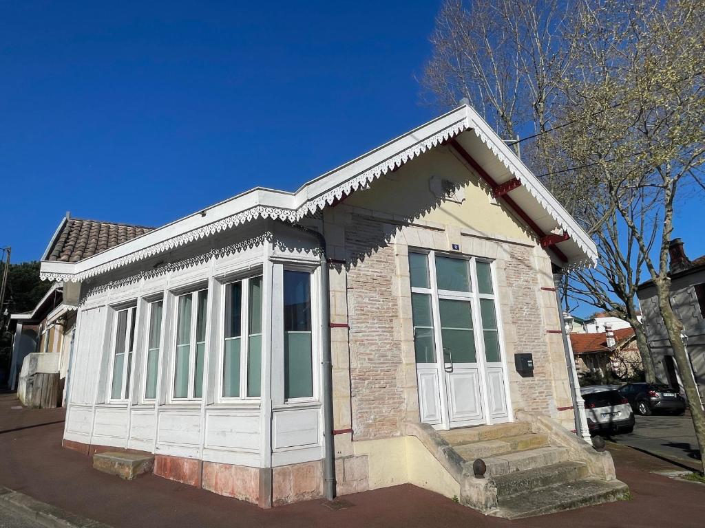 - un petit bâtiment avec des portes et des fenêtres blanches sur une rue dans l'établissement Maison 4 chambres avec clim, Wi-Fi à 5 min de la plage à Arcachon - FR-1-420-124, à Arcachon