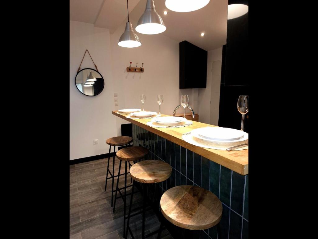uma cozinha com um bar com bancos e pratos em Maison individuelle cosy em Argenteuil