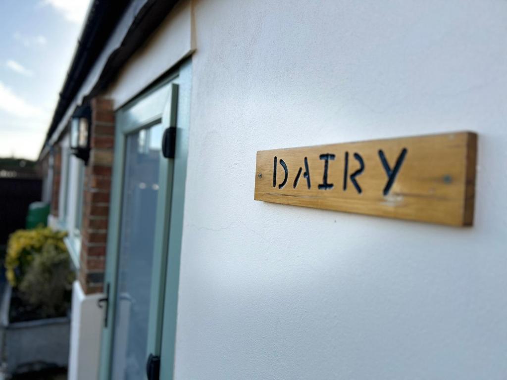 una señal que dice lácteos en un lado de un edificio en The Dairy, Bramble Farm Cottages, en Ferndown