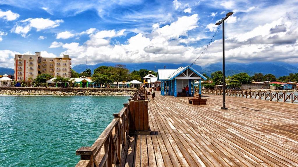 a wooden pier with a building on the water at Villas del Mar in La Ceiba