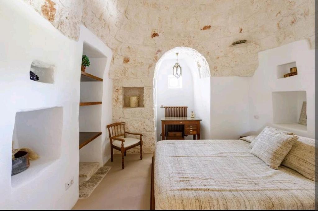 une chambre avec un grand lit et un bureau dans l'établissement Trullo Zurlo, à Ostuni
