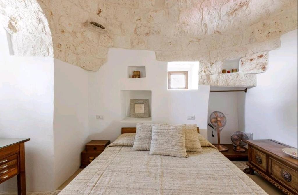 une chambre avec un grand lit dans une pièce blanche dans l'établissement Trullo Zurlo, à Ostuni
