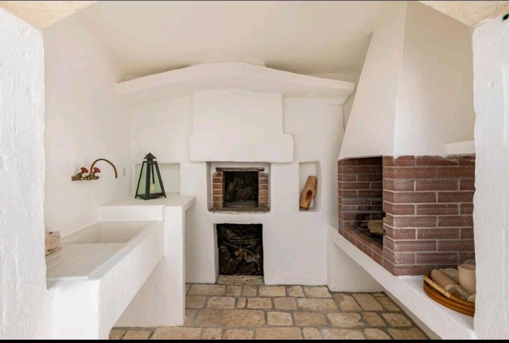 Cette chambre blanche dispose d'une cheminée et d'un lavabo. dans l'établissement Trullo Zurlo, à Ostuni