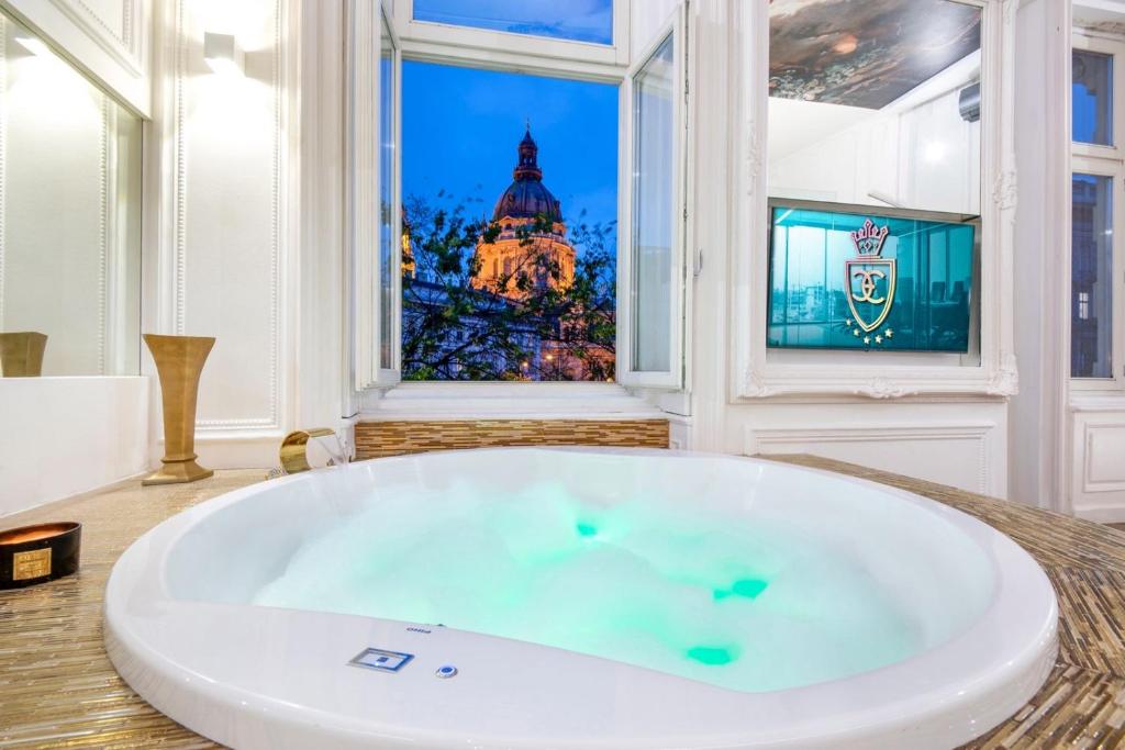 a large white tub in a room with a window at ENZO CAPO VIP suite in Budapest