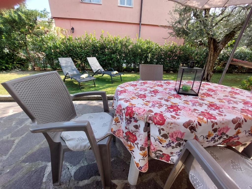 Appartamento Oasi Verde Lago في ديسينسانو ديل غاردا: طاولة عليها قطعة قماش من الزهور مع كراسي