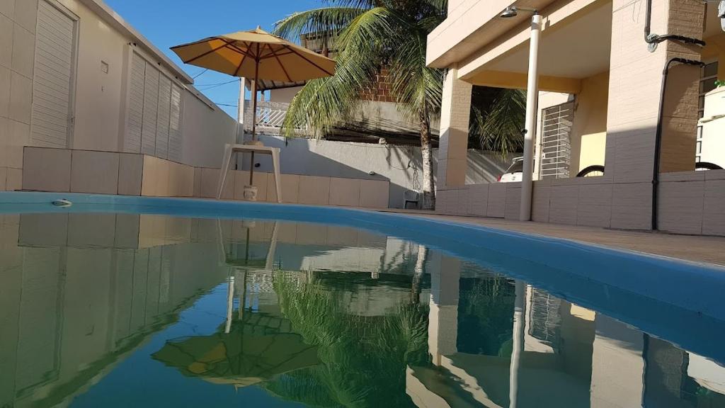 a pool with an umbrella next to a building at Residencial Caetano em Porto de Galinhas in Porto De Galinhas