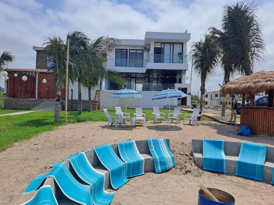 un grupo de sillas y sombrillas en una playa en Hermosa casa frentes al mar en Montanita con piscina, en Montañita