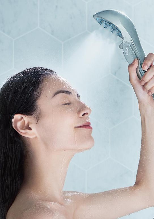 a woman in the shower holding a hair dryer at Richmond Hotel Yokohama-Bashamichi in Yokohama