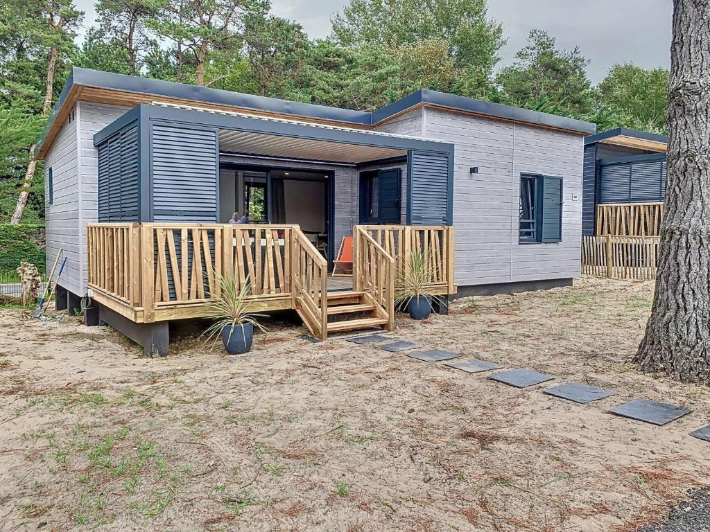 une petite maison avec un porche et une terrasse dans l'établissement Chalet à Jullouville - 6 couchages, piscine chauffée, proche plage et commerces - FR-1-361-521, à Jullouville