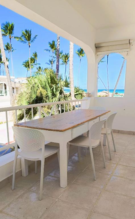 a wooden table and chairs on a patio with palm trees at Flor del Mar Condo Punta Cana Beachfront in Punta Cana