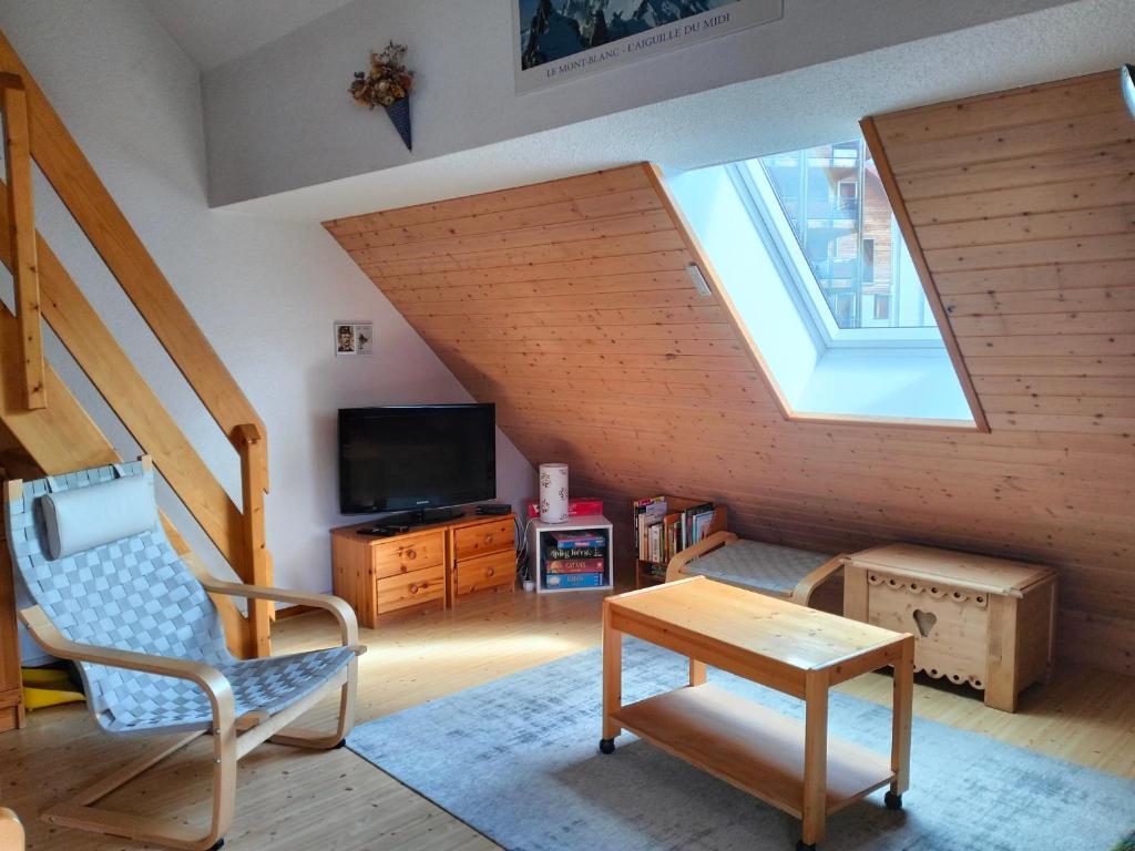 un salon avec une chaise et une télévision dans l'établissement Charmant T2 à Villard-de-Lans, proche centre, balcon sud, parking privé, idéal pour 4-6 pers. - FR-1-761-20, à Villard-de-Lans