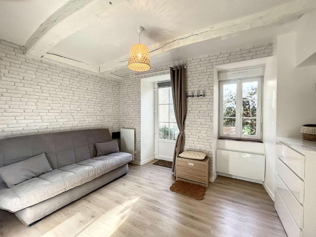 a living room with a couch and a brick wall at Studio Granville, 1 pièce, 2 personnes - FR-1-361-526 in Granville