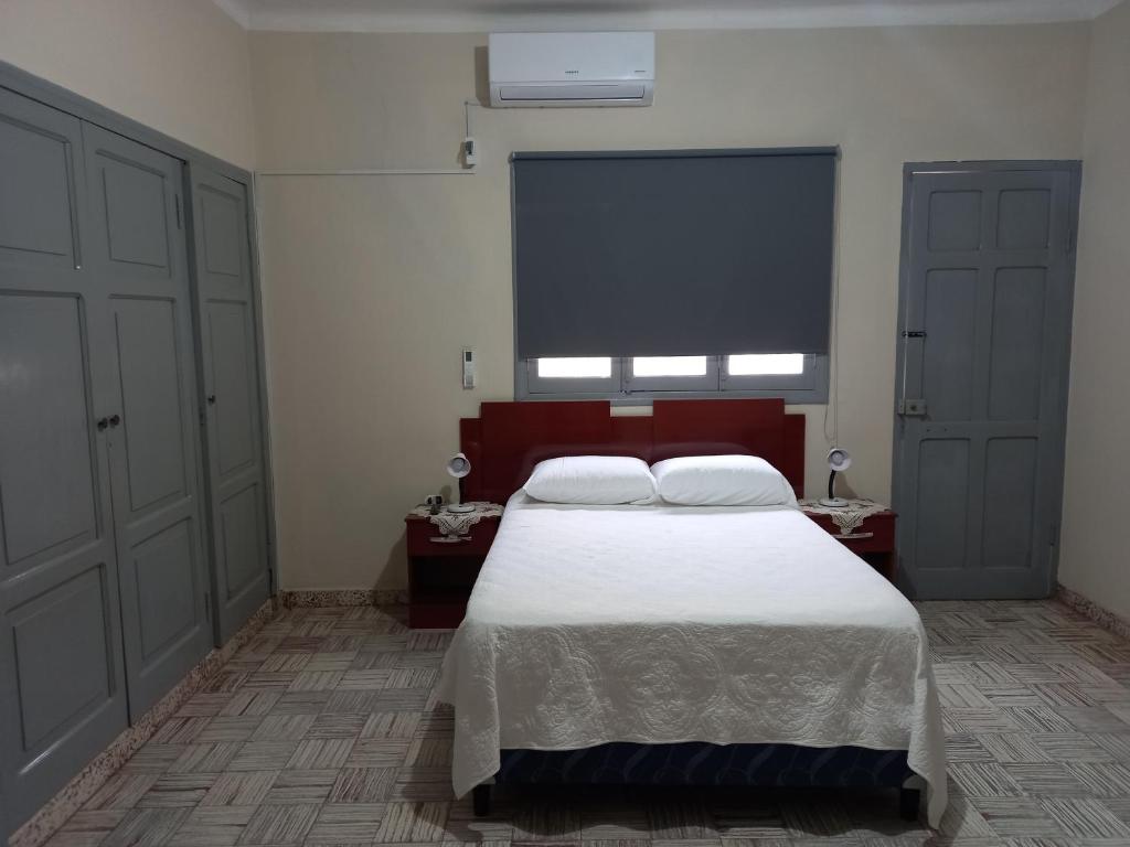 a bedroom with a white bed and a large window at Martin Barroso in Yacuiba