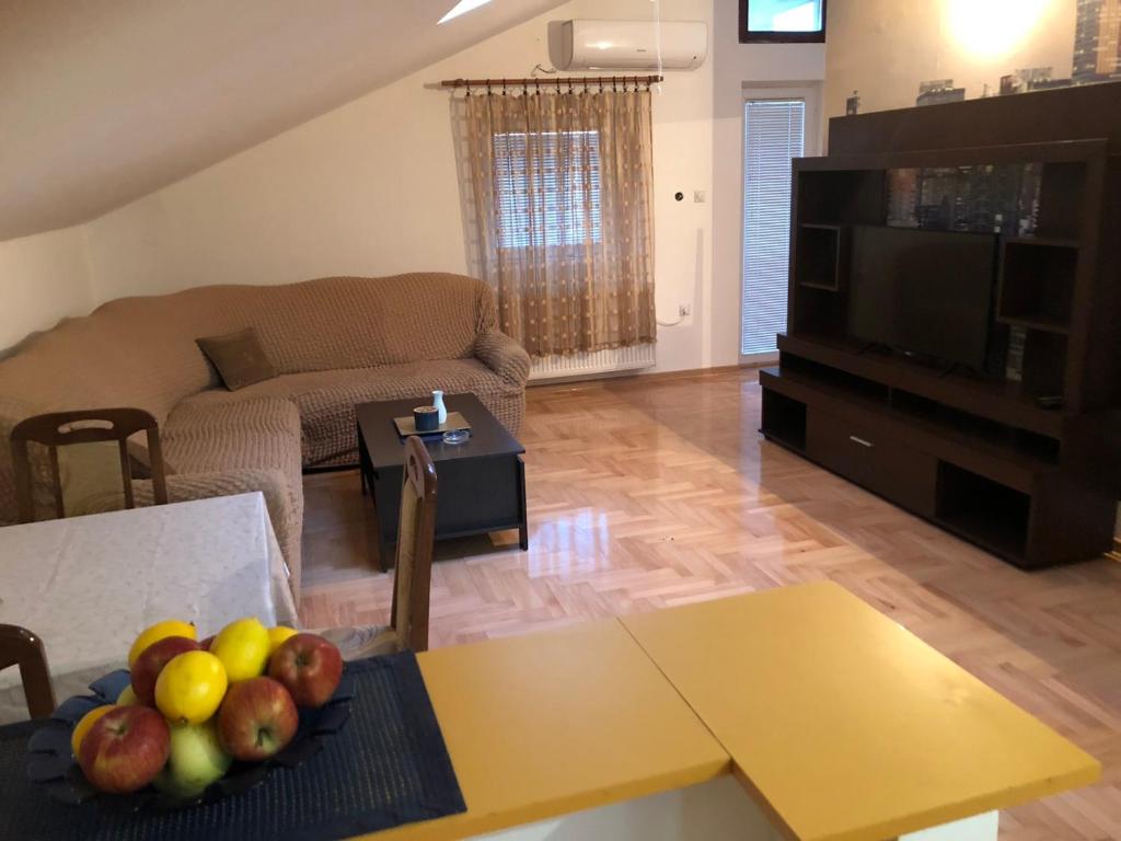 uma sala de estar com um sofá e uma mesa com frutas em Apartman Altina M em Zemun Polje