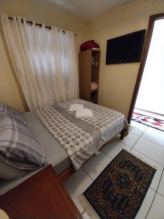 um pequeno quarto com uma cama e uma janela em Apartamento no centro em Canela