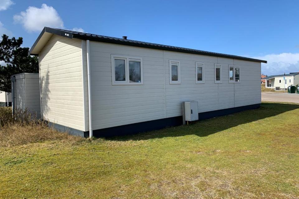 ein kleines weißes Gebäude auf einem Grasfeld in der Unterkunft Chalet Overtime in Buren