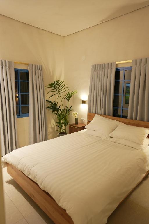 Schlafzimmer mit einem großen weißen Bett und Fenstern in der Unterkunft MORI HOUSE in Bet Scheʼan