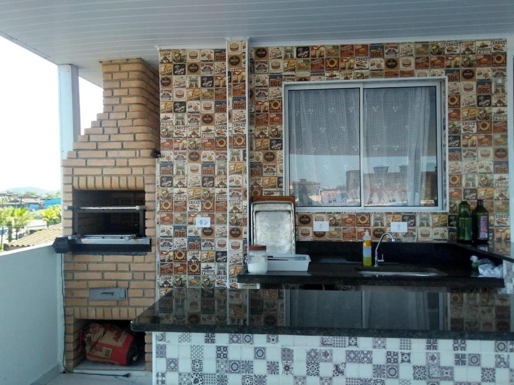 uma cozinha com uma parede de azulejos e uma janela em Familia Rodrigues no Guarujá