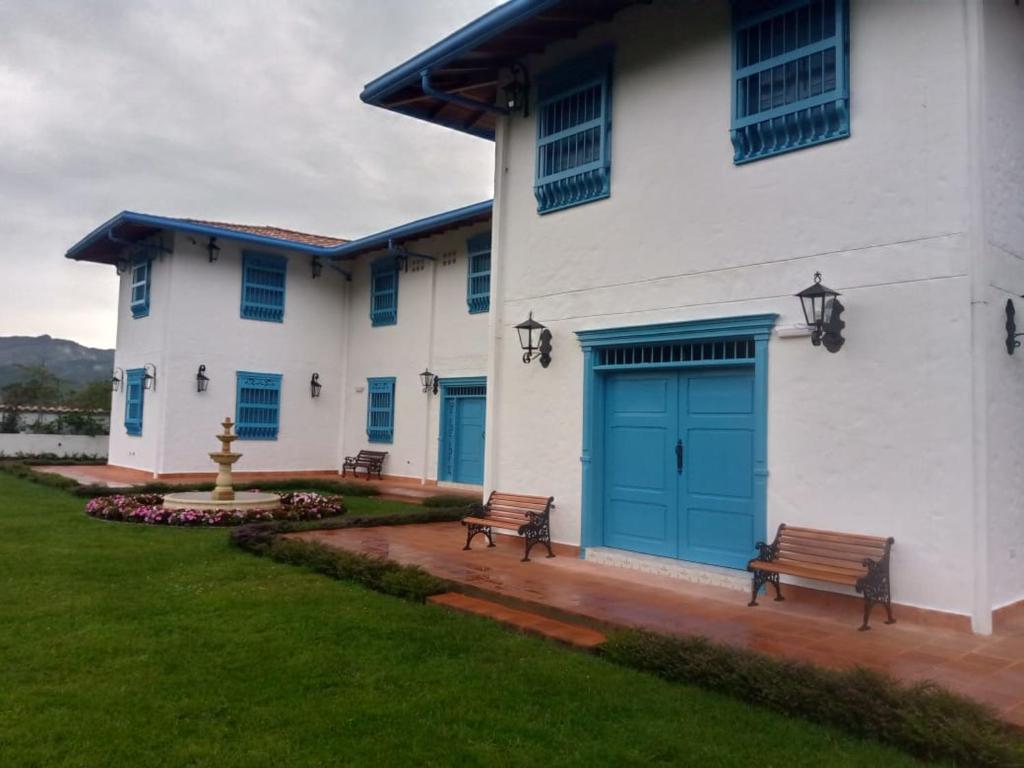a white building with a blue door and two benches at Hotel Concepción Antioquia in Concepción