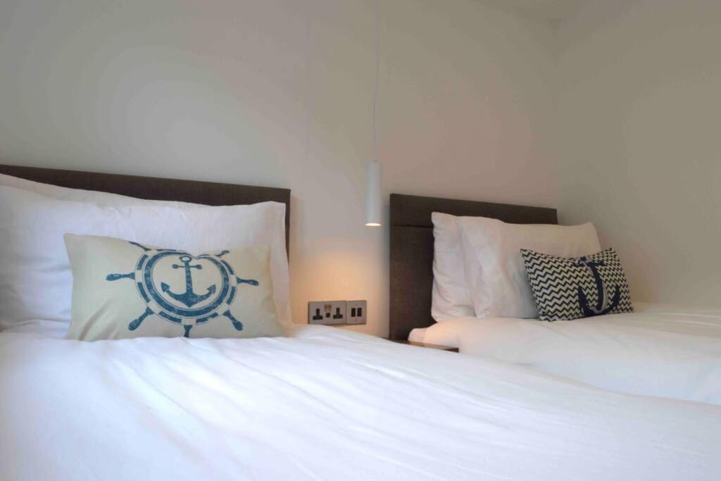 a bedroom with two beds with white sheets and an anchor pillow at Riverside House Lancaster - 2 bedroom house in Lancaster