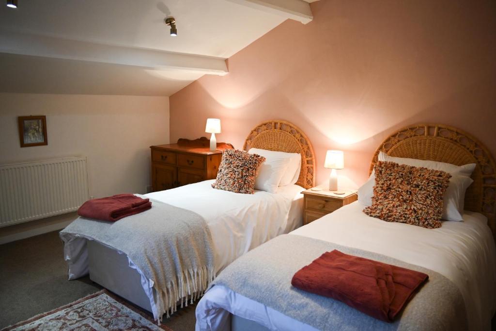a bedroom with two beds with white sheets and leopard pillows at Gardener's Cottage in Lancaster