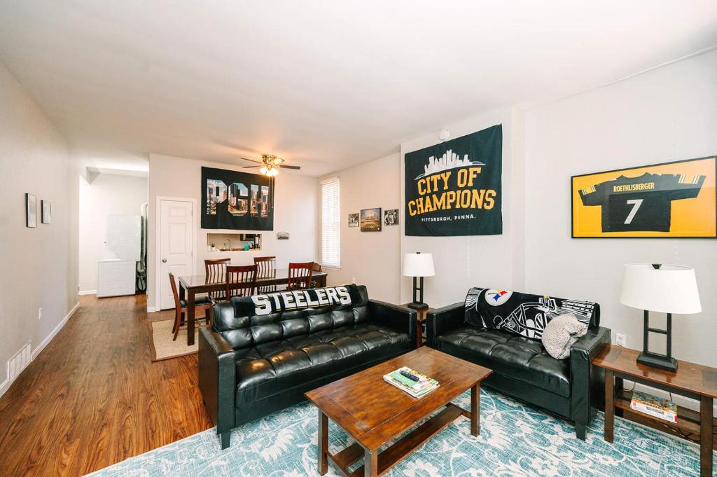 a living room with a black leather couch and a table at Pittsburgh's Sports Suite- FREE driveway Parking in Pittsburgh