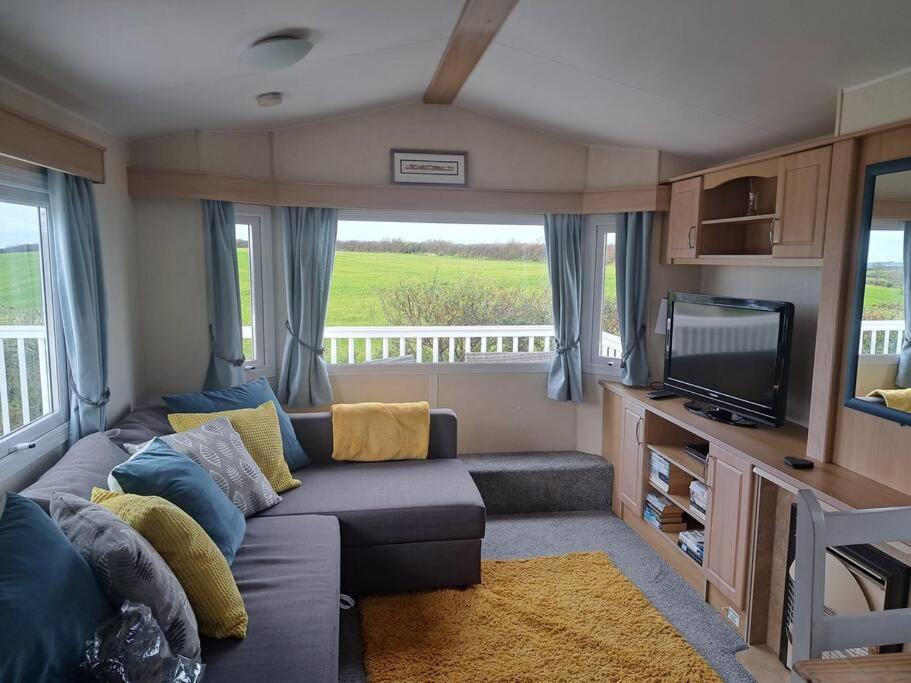 a living room with a couch and a tv at Cosy home with stunning views in Holsworthy
