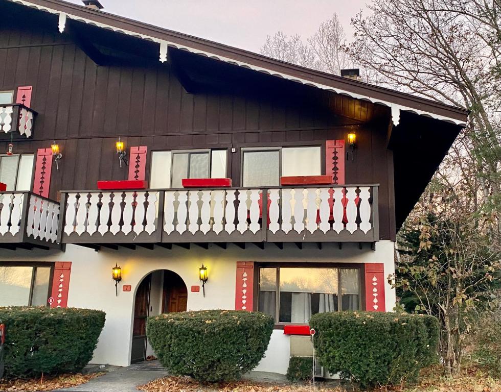 ein Haus mit roten und weißen Zierleisten und einem Balkon in der Unterkunft White Mountain Escape - Ski Attitash in Bartlett