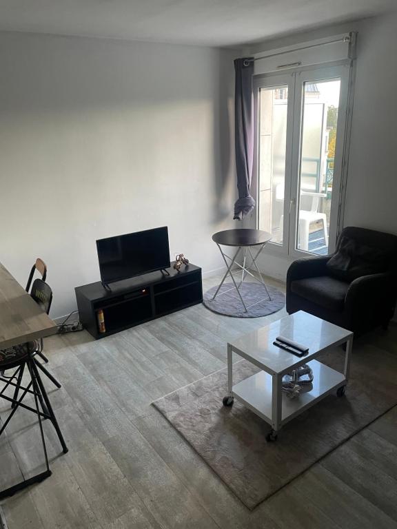 uma sala de estar com um sofá e uma mesa em Appartement cosy en plein centre-ville em Évry-les-Châteaux