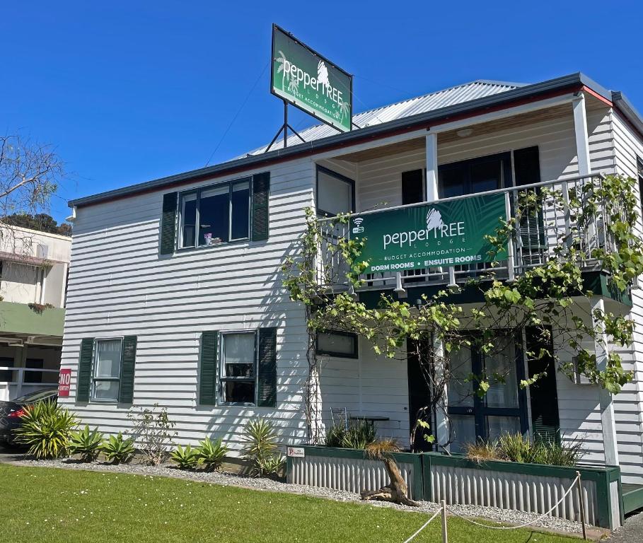 a white building with a sign on top of it at Peppertree Lodge & Backpackers in Paihia