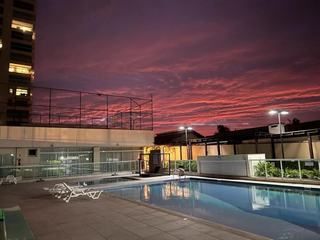 un edificio con piscina por la noche en Velutti Home Club - Conforto Lazer e Vista Pro Mar, en Penha