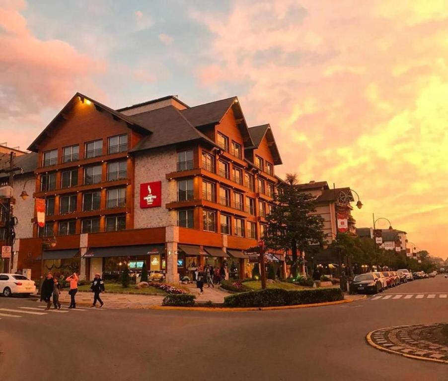 a building on the corner of a street with people walking at Hotel Laghetto Stilo Borges in Gramado