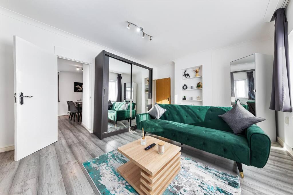 ein Wohnzimmer mit einem grünen Sofa und einem Tisch in der Unterkunft Ultra Elegant 2BDR - 10 mins to stadium - Sleeps 5 in London