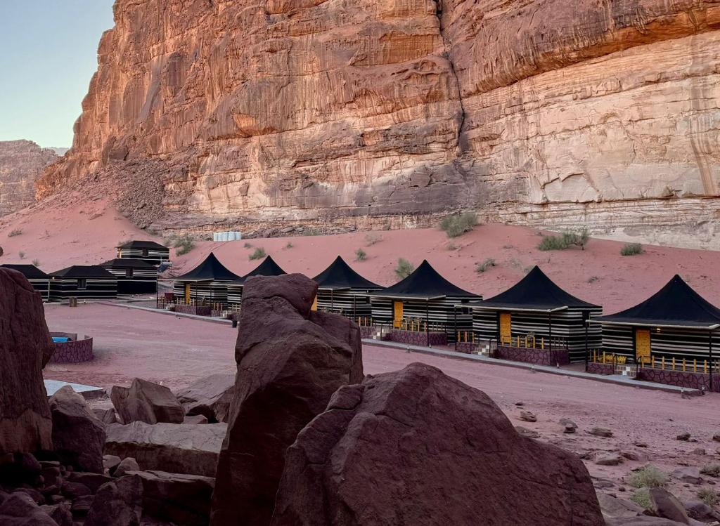 a building with a mountain in the background with rocks at STARDUSt CAMP in Wadi Rum