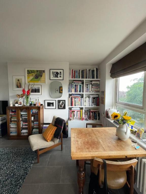 a living room with a table and a book shelf at Contemporary 1BD Flat wBalcony - Stoke Newington! in London